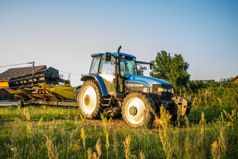Plave traktor marke TM125 NEW HOLLAND s alatom za oranje