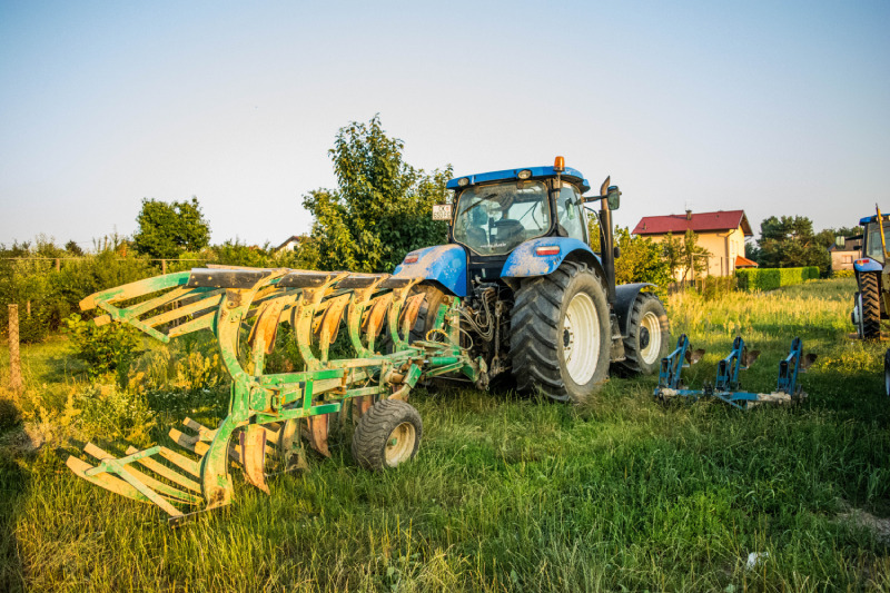 Plavi traktor marke TM125 NEW HOLLAND s alatom za oranje